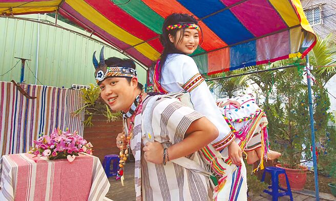 花莲县秀林乡富世村可乐部落11日举办一场太鲁阁族传统婚礼，新郎尤黄柏硕（左）以「巴卡（paga）」背着空姐新娘林怡妏（右）走入婚礼会场，象徵男方往后有能力让女方过好日子。（民眾提供／罗亦晽花莲传真）
