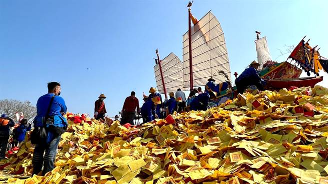 庙方和信眾合力为王船添载纸扎的神兵神将，船底下方则堆迭壮观的金纸山。（张毓翎摄）