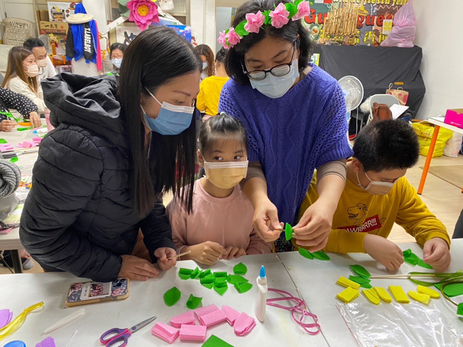菲律宾新住民罗戴娜(右二)教学手作花圈，参与民眾认真地聆听。(戴志扬翻摄)