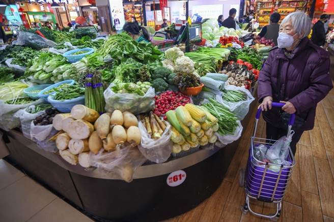 图为一名大陆民眾在一家农贸市场内选购蔬菜。（摘自中新社）