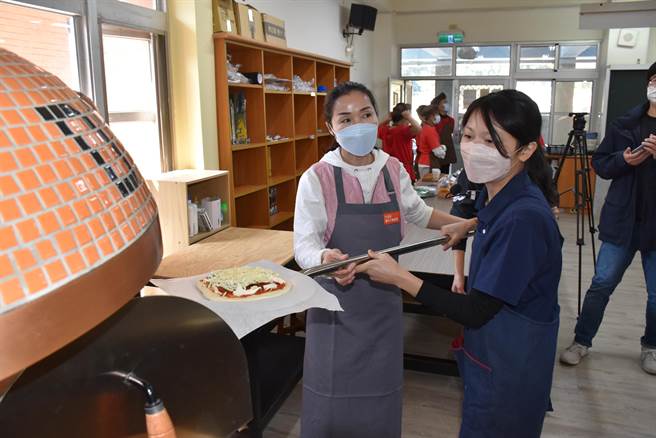 苗栗县长夫人陈美琦将手作完成的比萨送进烤窑。（谢明俊摄）