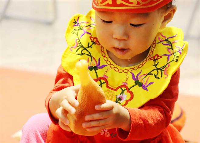 「城隍佑民，文昌护子」公益古礼抓周活动，今40位宝宝穿戴状元帽、平安虎围兜新奇体验抓周乐趣，抓到鸡腿的宝宝还忍不住流口水。（吕妍庭摄）