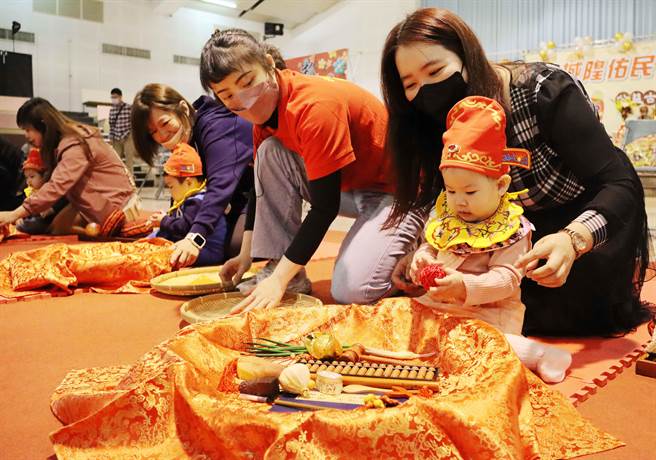 40位宝宝穿戴状元帽、平安虎围兜新奇体验抓周乐趣。（吕妍庭摄）