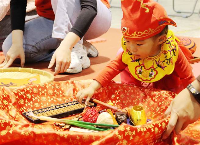 40位宝宝穿戴状元帽、平安虎围兜新奇体验抓周乐趣。（吕妍庭摄）