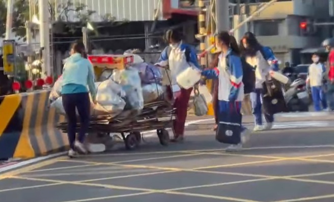彰化拾荒婦人日前推著沉重推車經過平交道時，因柵欄準備放下，警示燈響起，婦人仍在路中，這時有3名國中女生與1名女子衝上前幫忙推車。（翻攝自臉書「彰化踢爆網」）