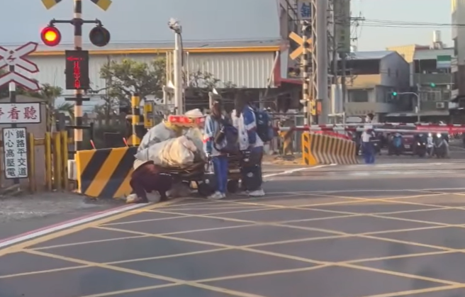 彰化拾荒婦人日前推著沉重推車經過平交道時，因柵欄準備放下，警示燈響起，婦人仍在路中，這時有3名國中女生與1名女子衝上前幫忙推車。（翻攝自臉書「彰化踢爆網」）