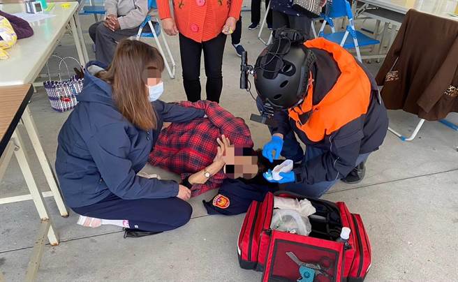 文健站老妇突晕眩倒地，池上暖警巫俞霈脱外套让她当头枕。（民眾提供）