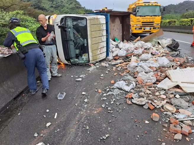 ▲基隆市中山高北上2公里处发生货车翻覆，车上载运的工程废弃物散落一地，驾驶左手臂多处擦伤。（基隆市消防局提供／徐佑升基隆传真）