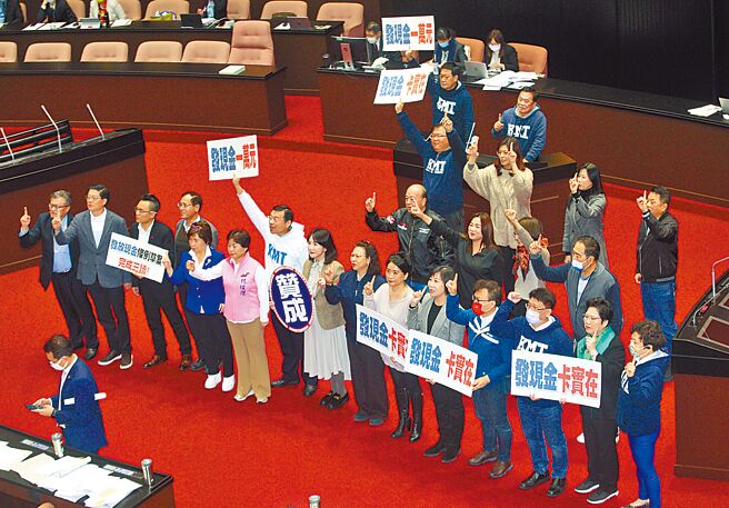立法院院会21日三读通过《疫后强化经济与社会韧性及全民共享经济成果特别条例》，国民党立委在议场手持「发现金一万元 发现金卡实在」等标语合影。（张铠乙摄）