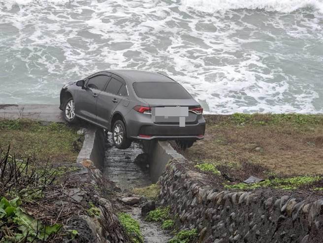 新北市万里区台二线旁的国圣埔凉亭附近，在今(23)日下午4时24分发现有辆轿车突然衝出道路，卡在海边的水泥排水道，仅差一点就整车落海。(黄敬文翻摄)