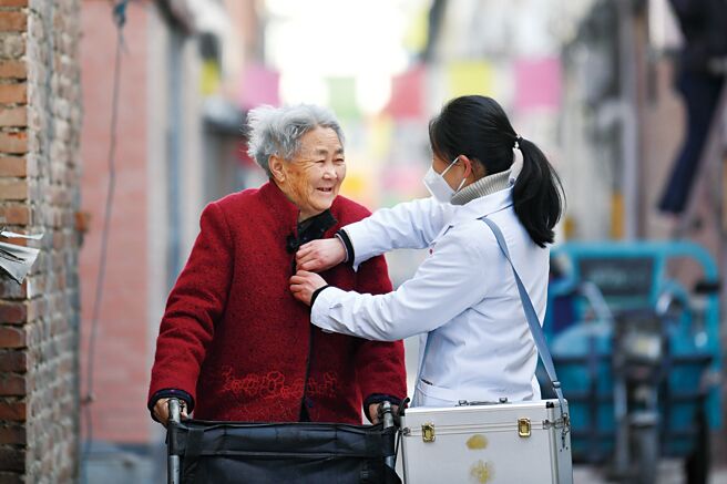 随着人口老化，大陆准备推动有关改革，包括退休年龄延后。图为大陆乡村医生冯旭辉（右）在随访的路上，问候一位老人健康近况。（中新社）