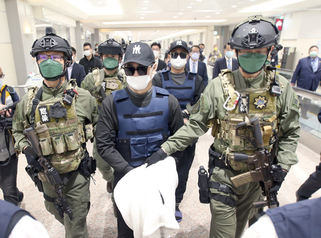 去年犯下台南学甲88枪枪击案主谋洪政军（前排中）及枪手孔祥志（后排右）25日回台，两人下机后由刑事局除暴特勤队员押解至机场入境大厅前，再移交给台南市警局。（范扬光摄）