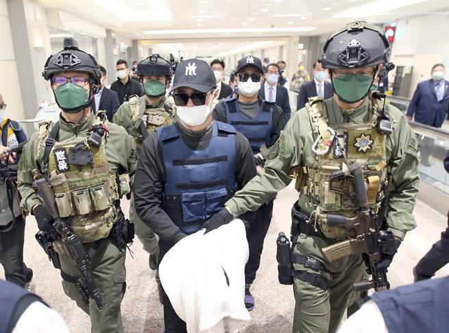 学甲枪击案主谋洪政军（前排中）及枪手孔祥志（后排右）25日回台，两人下机后由刑事局除暴特勤队员押解至机场入境大厅前，再移交给台南市警局。（范扬光摄）