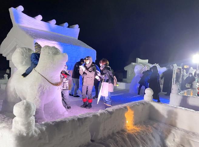 夜晚的雪雕在灯光照射下，呈现不同梦幻氛围。（何书青摄）