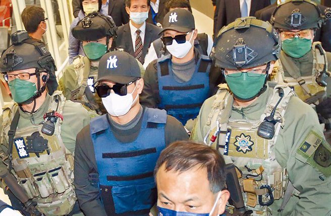 台南学甲枪击案主谋洪政军（前排中）及枪手孔祥志（后排中）25日回台，两人下机后由刑事局除暴特勤队员押解至机场入境大厅前，再移交给台南市警局。（资料照片/范扬光摄）