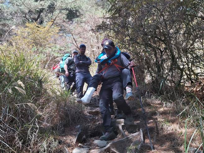 美籍女性登山客脚踝受伤无法行走，消防弟兄等背负下山，运至池有山登山口后，由梨山92送往梨山卫生所救治。（台中市消防局提供）
