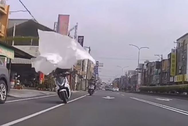 一名骑士行驶在高雄市路竹区纵贯公路上时，突然一块白布飞来，差点害骑士摔车。（翻摄自YouTube频道「WoWtchout - 地图型行车影像分享平台」）
