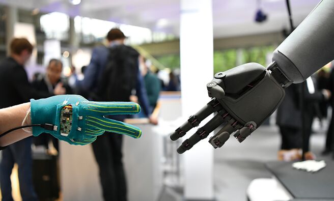 人工智慧聊天机器人正夯，大陆学者认为，未来科技演算等大幅改变民眾生活，并影响国际政治。图为一款可感知人类手势的智慧机器人（右）与观眾互动。（新华社）