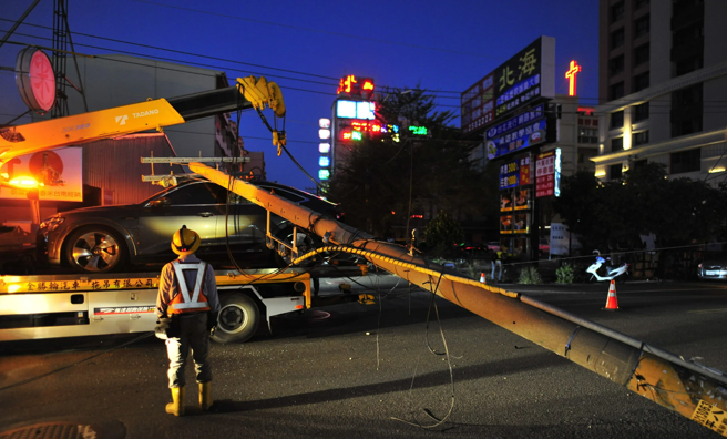 奧迪車主請拖吊業者將車子拖回原廠時，拖吊車才剛駛離約30公尺，就因為吊臂未收，導致勾到一旁電線，將電線桿扯斷，電桿還剛好砸在奧迪車上。（翻攝照片）