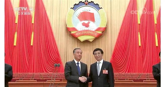 全国政协主席汪洋（左）在昨日宣布结束预备会议议程后，获推选为主席团会议主持人的中央政治局常委王沪寧（右）随即走上主席台，与汪洋握手。（央视截图）