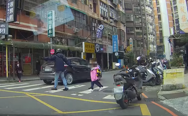 林口一處路口日前發生一對幼童準備過斑馬線時，遭大量左右來車嚇到，退後好幾步不敢往前，最後是一名好心騎士見狀下車幫忙指引。（翻攝自臉書「林口大家庭」）