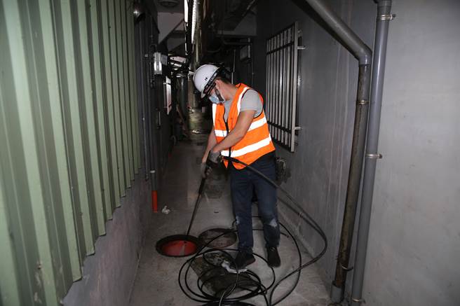 新北市水利局利用引擎式高压清洗机以高压水柱对附着油腻腻的污水管壁冲洗，去除厚厚油脂。（新北市水利局提供）