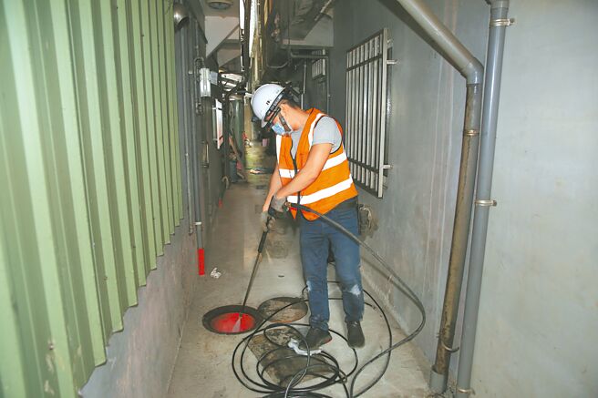 新北市水利局利用引擎式高压清洗机，以高压水柱去除堵塞下水道的厚厚油脂。（新北市水利局提供／陈慰慈新北传真）