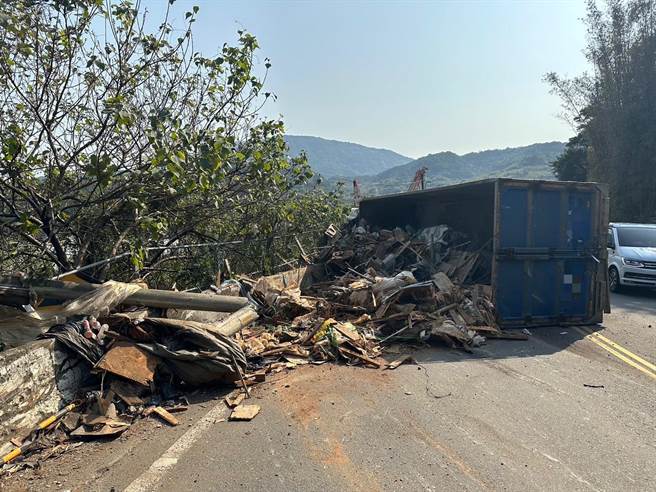 有輛載滿廢棄物的貨車今(8)日早上沿新北市八里區後湖路，往八里方向行駛時，疑似煞車失靈，結果在轉彎時擦撞護欄翻覆。(黃敬文翻攝)