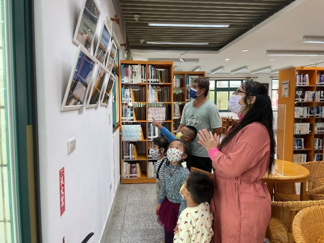 幼儿邀请家长到图书馆观赏摄影展并热情解说。(照片/新北市教育局提供)