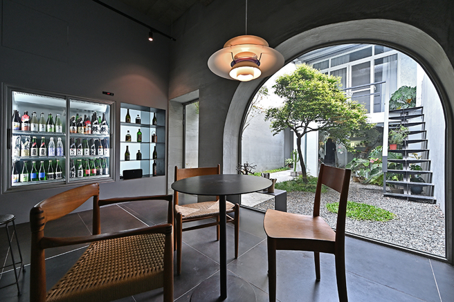 吧台後方空間是屋物清酒店內最受歡迎的位置，水泥拱型窗環抱中庭綠意，坐在丹麥設計師經典椅上，品飲清酒與春光，極為愜意。(攝影/Carter)