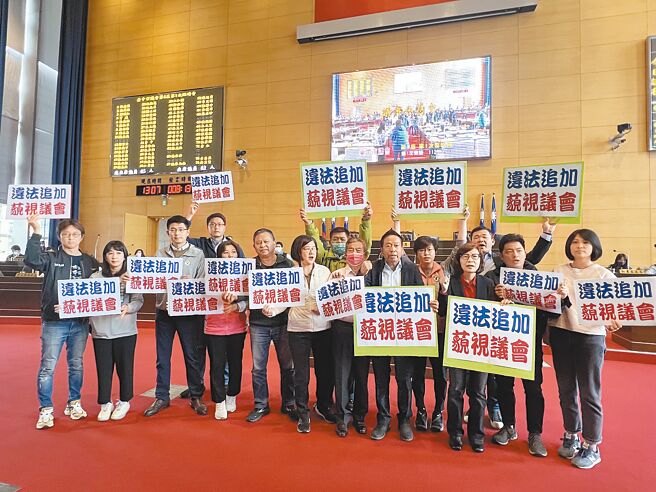 民进党台中市议会党团举牌站到议事台前，要求退回科目为「消费金喜送」的台中购物节3.5亿追加预算。（林欣仪摄）