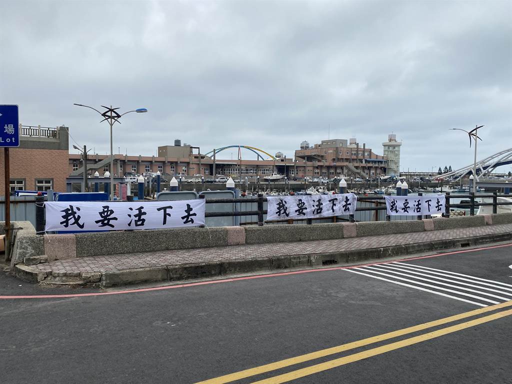 漁民在永安漁港路邊掛上白色布條，寫上「我要活下去」表達抗議訴求。（蔡明亘攝）