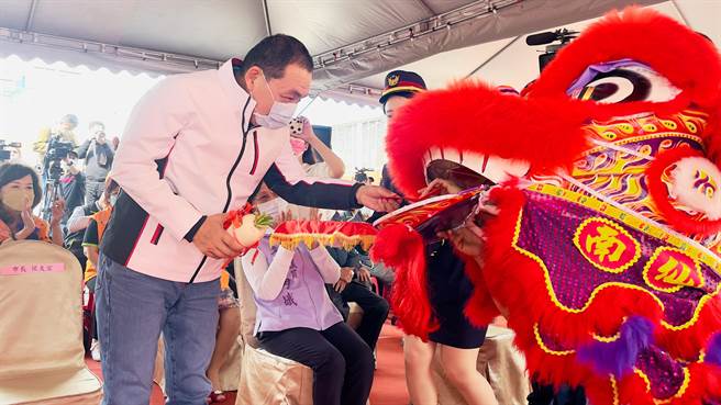 从舞狮口中接过白萝卜象徵好彩头。（吕健豪摄）