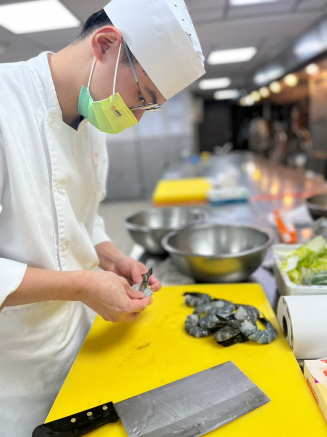 谢秉澄师傅专注处理食材-虎虾。（图/玄奘大学提供）