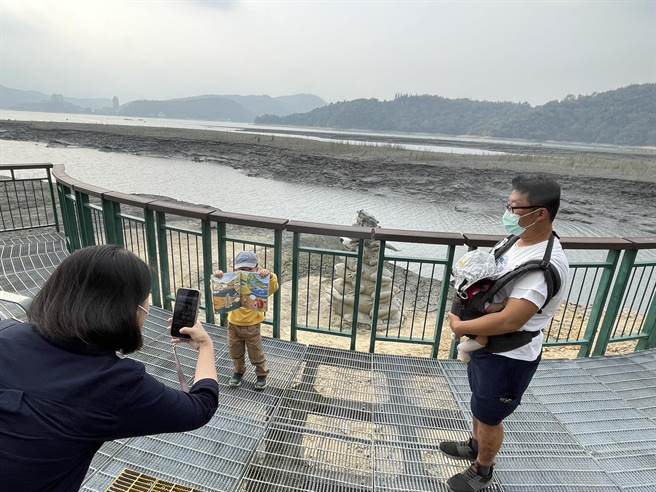 日月潭18日蓄水率剩54.6％，小朋友拿出九蛙迭像绘本，与日月潭的九蛙迭像合影。（杨静茹摄）