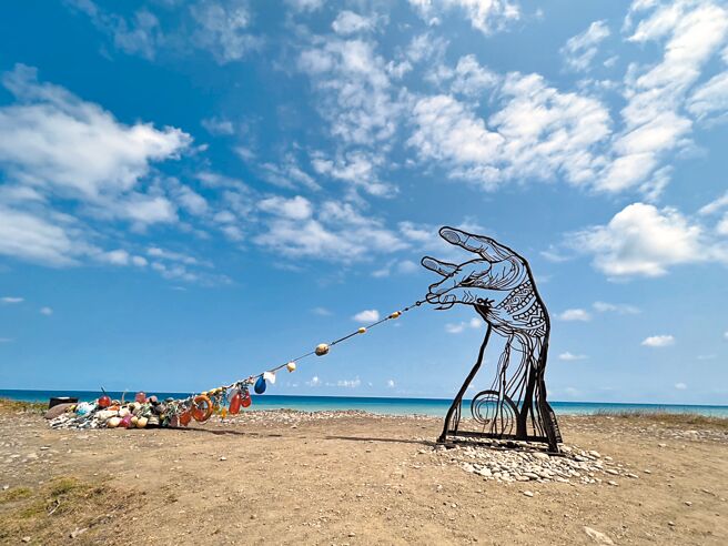 台东县达仁乡阿塱壹古道海边近日出现大型装置艺术，1只巨手拉起1串海漂物，吸引大批游客拍照打卡。（蔡旻妤摄）