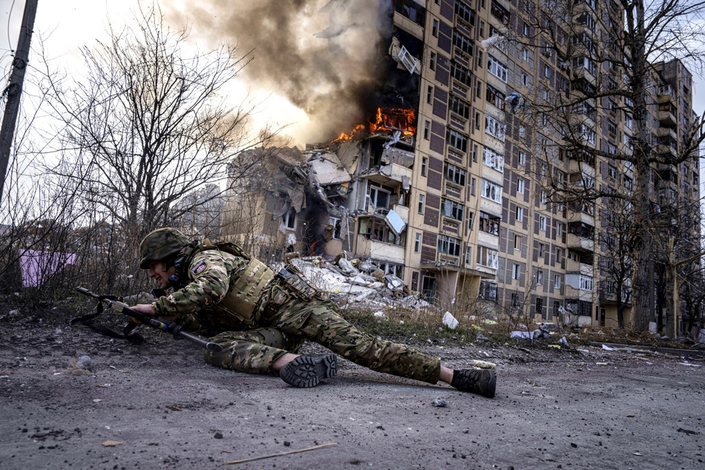 俄罗斯总统普丁19日称，他没有在2014年兼併克里米亚半岛时就全面入侵乌克兰，迟至8年后的2022年才展开行动，是因为俄罗斯当时在军事、经济方面都还没准备好。图为俄军17日空袭乌东城镇阿夫迪夫卡（Avdiivka），一名乌克兰警察寻求掩护。（资料照／美联社）(photo:ChinaTimes)