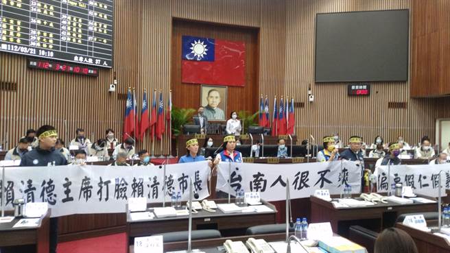 民进党台南市议会议长邱莉莉因涉正副议长贿选案遭起诉后，首次进议会主持，国民党团拉起白布条抗议，要求邱莉莉离席。（读者提供 ／张毓翎台南传真）