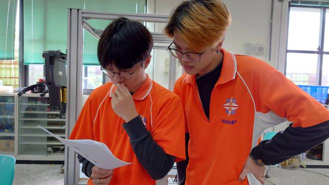 黄闵祥与吴冠伯两人正在讨论机器手臂的运作程式