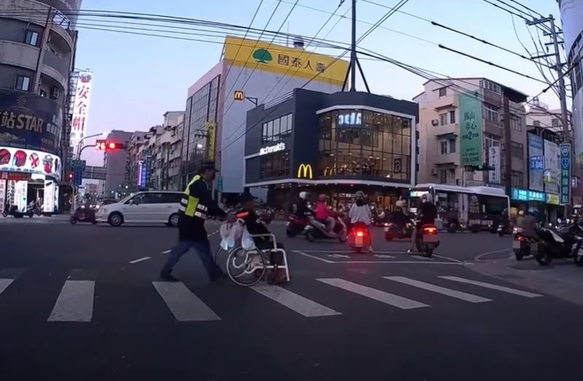 有骑士在高雄凤山一处路口看见执勤员警热心地推轮椅人士过马路，但却有网友则认为一旁满满的机车违停在骑楼、行人道，根本也无法让轮椅人士轻松通过。（翻摄自脸书八卦村 - 行车纪录器影片上传中心）