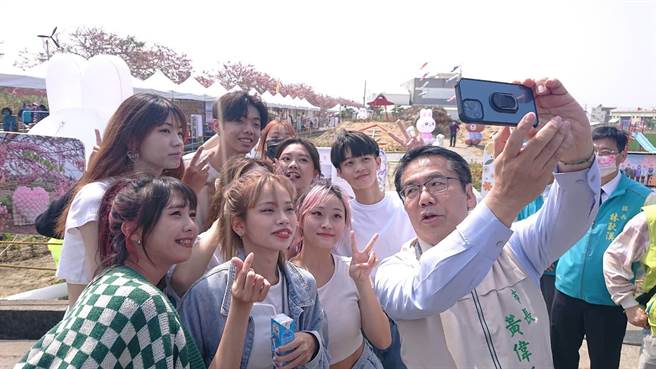 台南市長黃偉哲在金砂里花旗木大道前與年輕人玩自拍。（程炳璋攝）