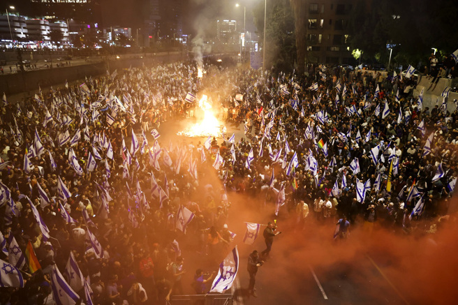 上万以色列人26日深夜霸占特拉维夫一座高速公路抗议，在公路上燃烧废弃物。（图／美联社）