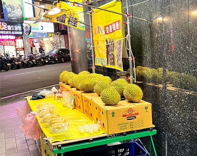 謝男（62歲）日前在萬華區的銀行前擺設攤位賣榴槤。（簡銘柱翻攝）