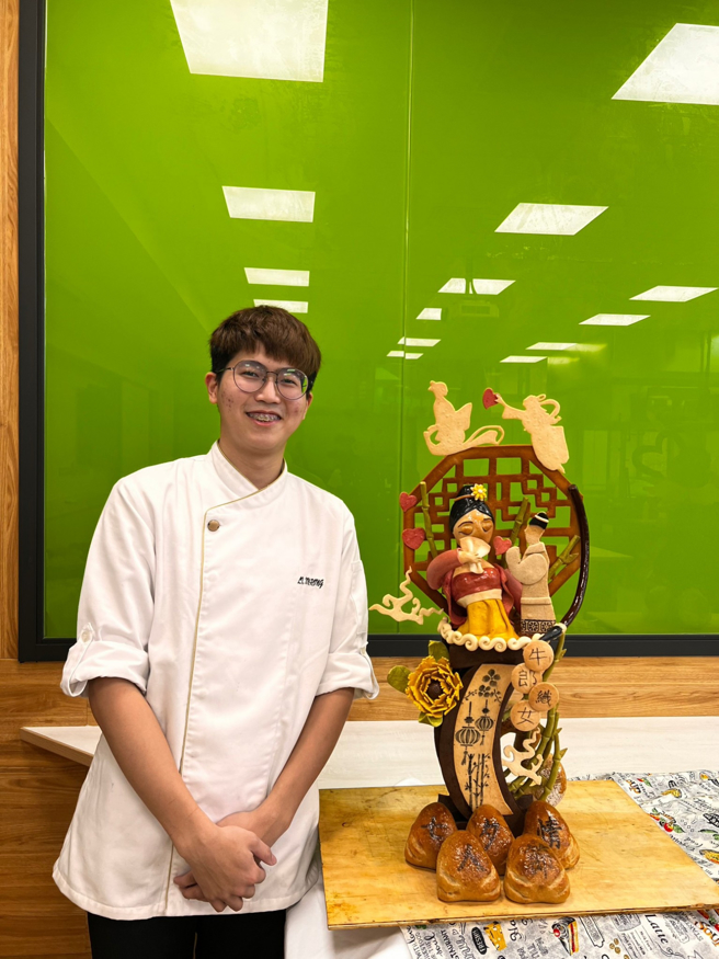艺术麵包设计第一名李昕融同学与参赛作品「情人节星织情缘」合影。(照片/中臺科大提供)

