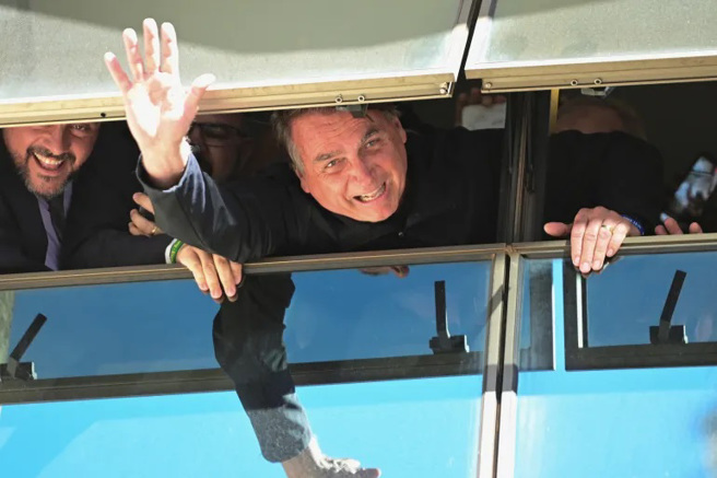 波索纳罗在巴西利亚国际机场，向支持群眾挥手致意。(图/路透社)