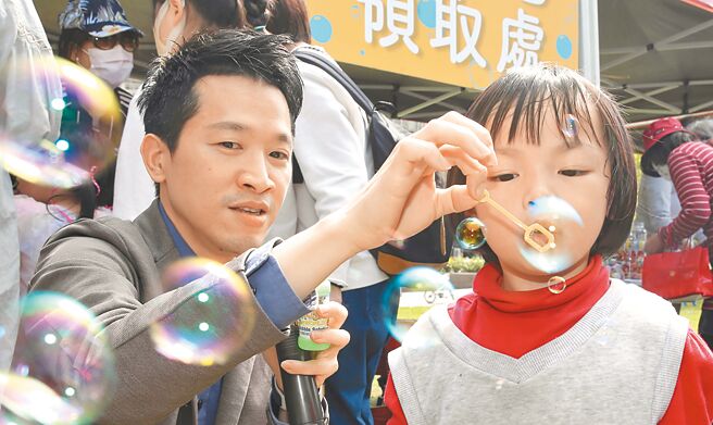 儿童节即将来到，立委何志伟（左）2日在建成公园的儿童游戏场举办亲子派对，带领小朋友一起吹泡泡提前庆祝儿童节，在党内初选开始前争取民眾支持。（陈怡诚摄）