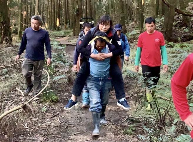 搜救队员轮流将扭伤脚的彭姓女子背至祝山线铁路，再以台车、救护车接驳送医。（南投县消防局提供／杨静茹南投传真）