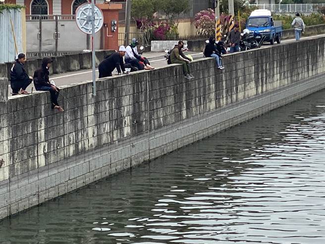 移工坐在石笱排水护岸垂钓，见鱼儿上钩再跳回岸边。（孙英哲摄）