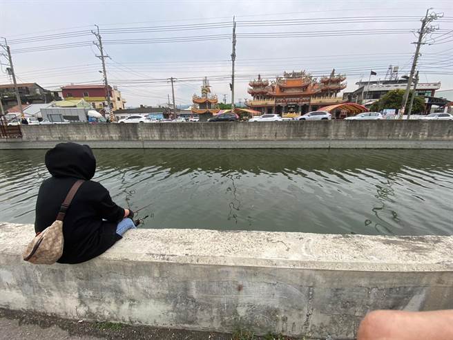 移工坐在石笱排水护岸垂钓，等待鱼儿上钩。（孙英哲摄）