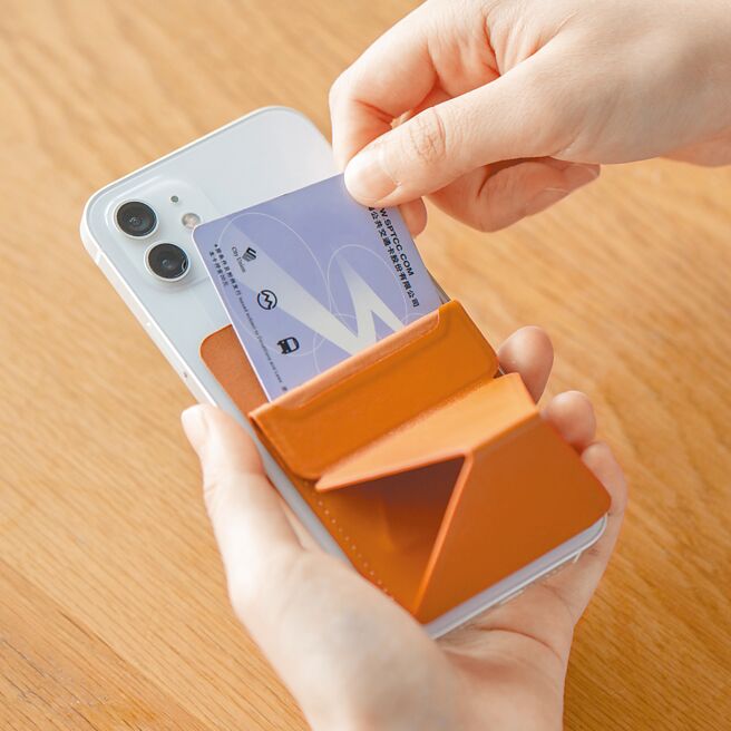 MUJI无印良品的手机支架（见图）有横竖两种支撑模式，且能收纳卡片，适合都会移动生活。产品材质来源是使用苹果榨汁后的残渣与树脂混合制成的合成皮革，共有白、黑、橘3色，预计售价399元，5月上市。（MUJI提供）
